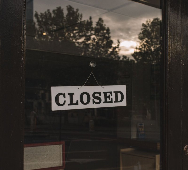 A closed sign hanging on a glass shop door