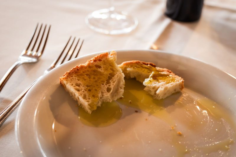 Pieces of bread dipped in golden olive oil on a white plate