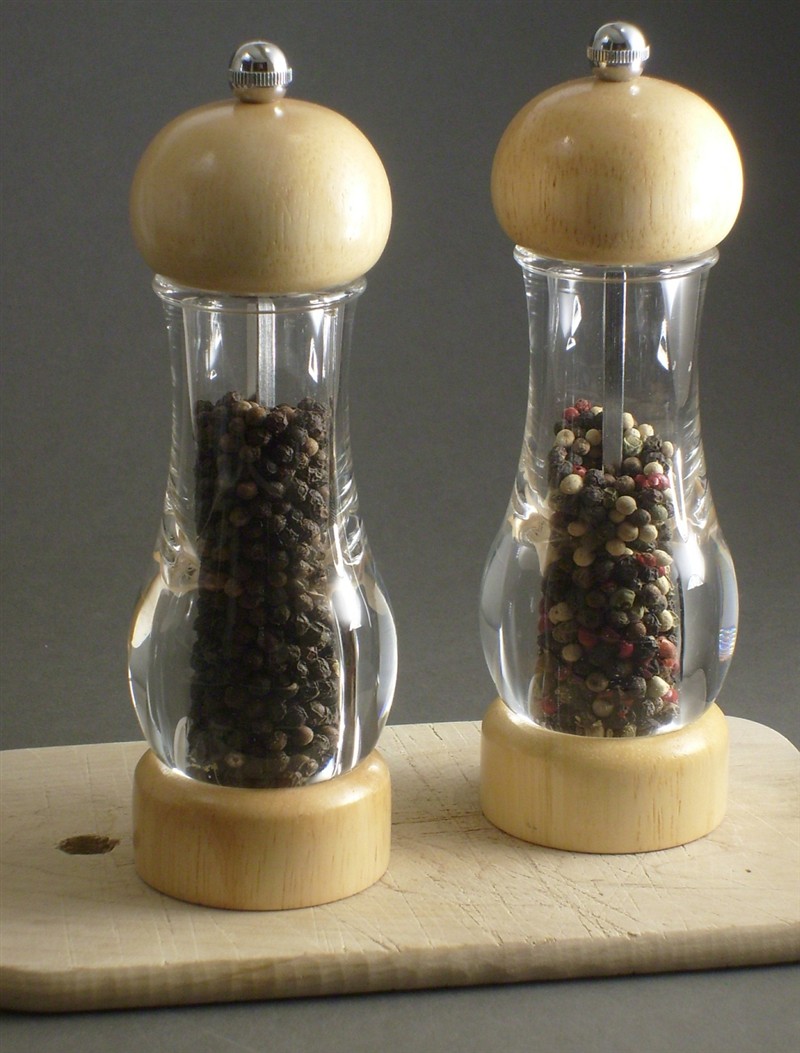 Two clear pepper mills, one filled with black peppercorns and one with a mix of black, white, and red peppercorns